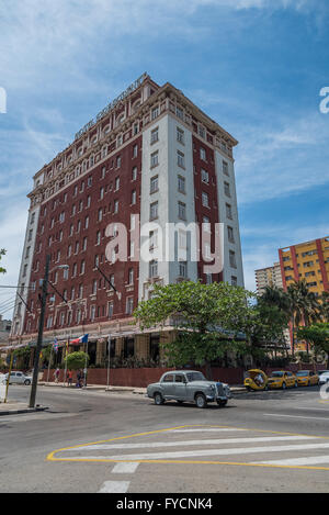 L'Hotel Presidente torreggia sopra l'Avenida de los Presidentes e una classica macchina che passa davanti. La Havana, Cuba Foto Stock