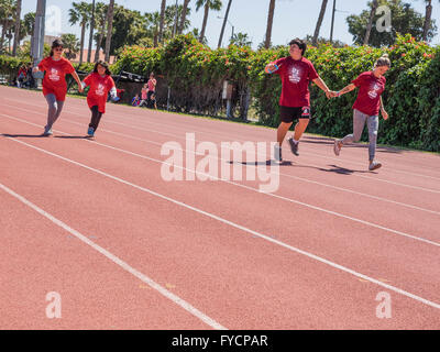 Aiutanti adulti aiutano i bambini disabili in gara 50 metri di gara presso la Southern California Special Olympics tenutasi a Santa Barbara, CA. Foto Stock