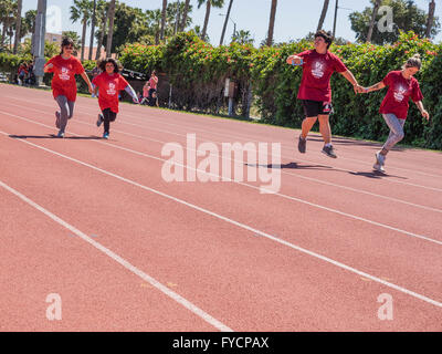 Aiutanti adulti aiutano i bambini disabili in gara 50 metri di gara presso la Southern California Special Olympics tenutasi a Santa Barbara, CA. Foto Stock