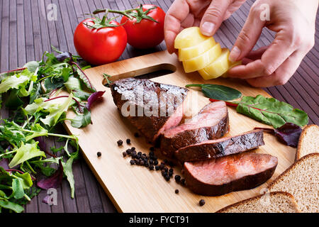 Close-up di mezzo raro arrosto di manzo con erbe aromatiche e verdure Foto Stock