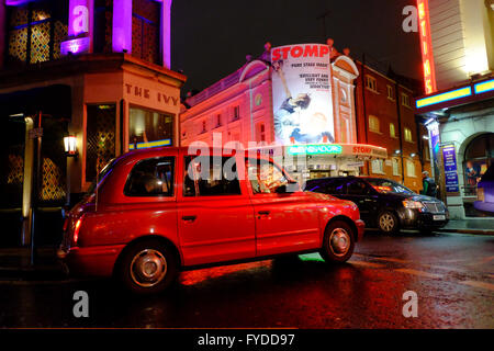 Rosso di arresto dei taxi al di fuori dell'edera ristorante con Ambassadors Theatre attraverso le strade di Londra Foto Stock