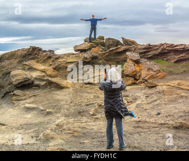 5 agosto 2015 - penisola di Reykjanes, Islanda - un turista femminile fotografie il marito in piedi sulla cima di rocce vulcaniche a Kleifarvatn, un profondo lago minerale con sommerso hot springs e in bianco e nero di spiagge di sabbia, sulla zona di fessura della Mid-Atlantic Ridge. Una destinazione preferita dai turisti, è il più grande lago sulla penisola di Reykjanes dell Islanda dove il turismo è diventato un settore in crescita dell'economia. (Credito Immagine: © Arnold Drapkin via ZUMA filo) Foto Stock