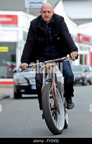 Bremerhaven, Germania. 22 apr, 2016. Christian Kelemen cavalca una bicicletta elettrica detenuti in stile del trinciatore con un particolarmente alto sella nella parte anteriore della sua officina biciclette presso il porto di pesca di Bremerhaven, Germania, 22 aprile 2016. Nel suo tempo libero, l'appassionato di sviluppatori e tinkerer è svolta regolarmente in biciclette e-bikes. Foto: INGO WAGNER/dpa/Alamy Live News Foto Stock