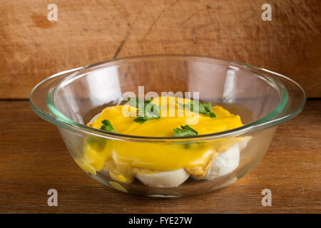 Vaso di vetro con uova ripiene o 'oua umplute' oltre rustico sfondo di legno Foto Stock