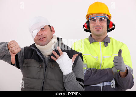 Un sano lavoratore edile in piedi accanto a un uomo ferito Foto Stock