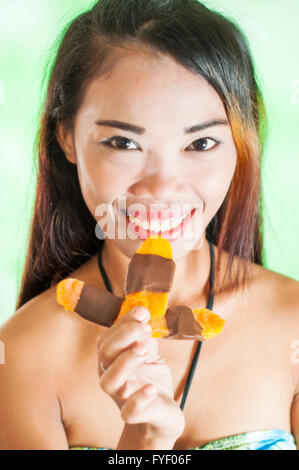 Slim giovane donna asiatica con mango barra di cioccolato Foto Stock