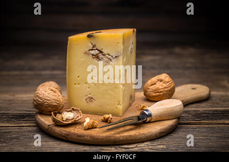 Pezzo di formaggio con le noci su pannello di legno Foto Stock