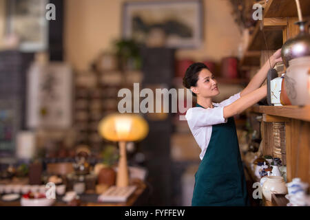 Casa da tè proprietario disponendo ripiano Foto Stock