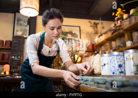 Casa da tè proprietario disponendo ripiano Foto Stock