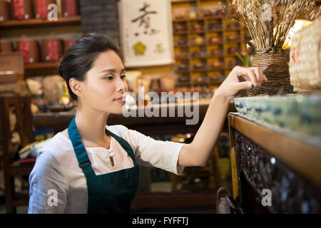 Casa da tè proprietario disponendo ripiano Foto Stock