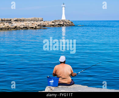 Cipro Nord KYRENIA pescatore in arancione sul muro del porto Foto Stock