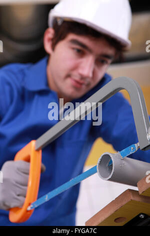 Giovane uomo è il taglio di un tubo in Pvc con una sega Foto Stock