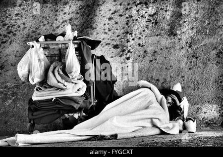 Senzatetto uomo dorme accanto al suo carrello sotto un cavalcavia autostradale di Austin, TX Foto Stock