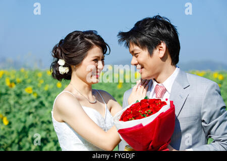 Ritratto di sposa e lo sposo vedendo ogni altro sul campo di girasoli Foto Stock