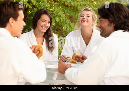 Due coppie condividono una barzelletta durante la prima colazione in giardino Foto Stock