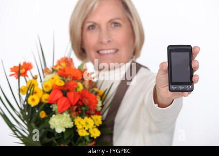 Anziani fioraio azienda fiori e telefono mobile Foto Stock