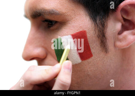 Man aventi la bandiera italiana dipinta sulla sua guancia Foto Stock