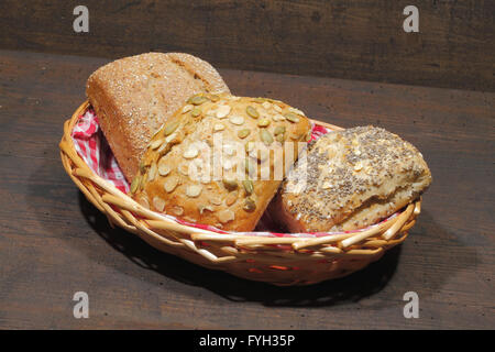 Vari tipi di pane, torte, bun, in un cestello, su un rustico, superficie in legno Foto Stock