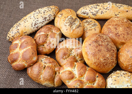 Diversi tipi di pane integrale e rotoli su sfondo marrone Foto Stock