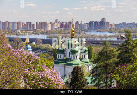 Duomo di San Giorgio del monastero di Vydubychi tra gli alberi del parco contro un moderno appartamento immobili molla. Kiev, Ucraina. Foto Stock