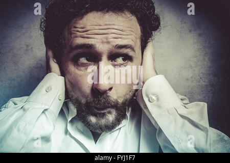 Imprenditore che copre le sue orecchie, Uomo in camicia bianca con espressioni buffe Foto Stock