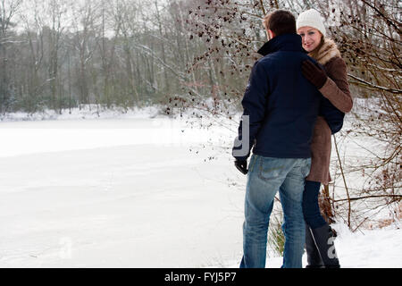 Gli amanti in piedi vicino a un lago ghiacciato Foto Stock