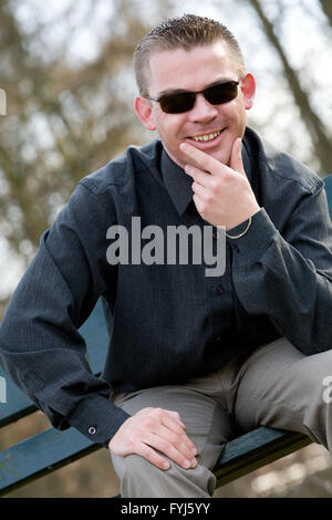 Giovane con occhiali da sole sorridente Foto Stock