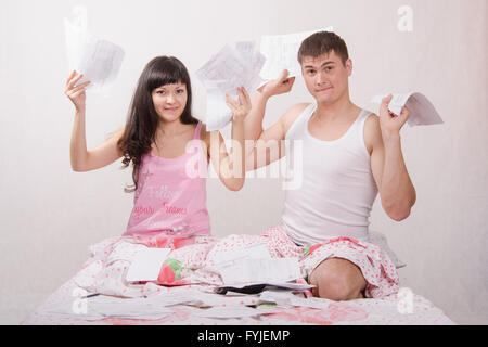 Famiglia giovane con fatture per appartamento si trova nel letto Foto Stock