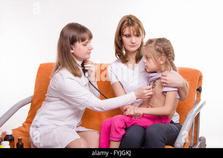 Pediatra controlli stetoscopio respiro una bambina nelle braccia della madre Foto Stock