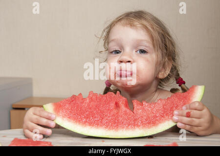 Due-anno-vecchia ragazza mangiando anguria con facce allegre Foto Stock