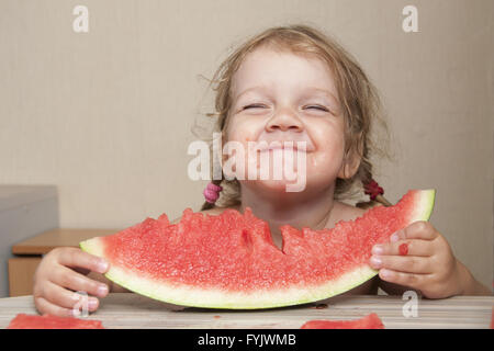 Due-anno-vecchia ragazza mangiando anguria con facce allegre Foto Stock