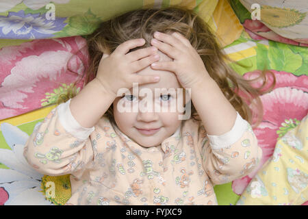 Due-anno-vecchia ragazza giacente sul letto e la testa tra le mani Foto Stock