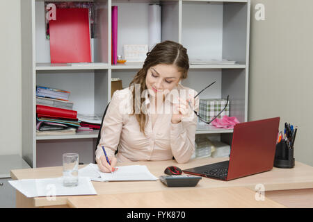 Ragazza scrive su un pezzo di carta in ufficio Foto Stock