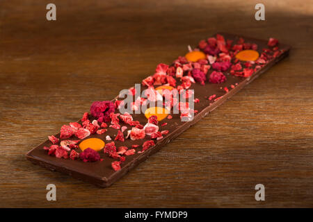 Arancia, fragola e lampone cioccolato al latte su sfondo di legno Foto Stock