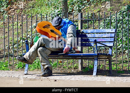 Praga, Repubblica Ceca. L'uomo addormentato su un banco di lavoro con una chitarra Foto Stock