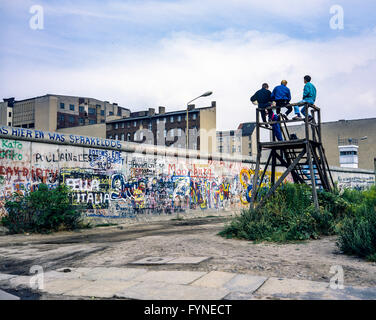 Agosto 1986, muro di Berlino graffitis, persone sulla piattaforma di osservazione guardando oltre il muro, Zimmerstrasse street, Berlino Ovest lato, Germania, Europa Foto Stock