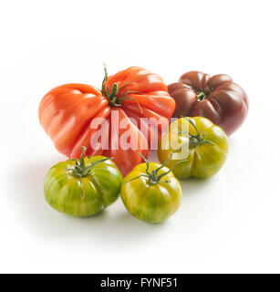 Un assortimento di cultivar di pomodoro fresco verde con tiger, coeur de boeuf e pomodori nero su sfondo bianco con copyspace Foto Stock