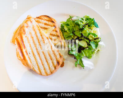 Spuntino tostato formaggio Cheddar e pomodoro in sandwich di pane bianco con insalata mista e smalto balsamico Foto Stock