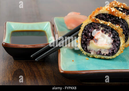 Nero rotoli di sushi servita sulla piastra di turchese Foto Stock