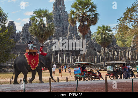 I turisti su elefante,tuk-tuks e tempio Bayon rovine, Angkor Thom (XII secolo complesso tempio), Angkor Sito Patrimonio Mondiale, si Foto Stock