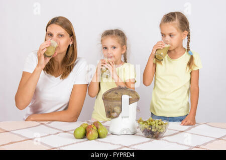 La madre e le sue due figlie bere succo fresco delle pere e delle uve Foto Stock