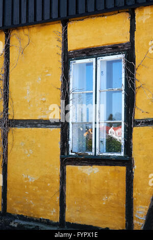 Piccola parte di una vecchia casa con travi di legno con una finestra incorniciata Foto Stock