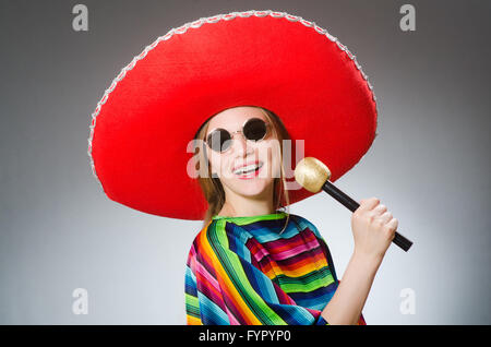 La ragazza di messicano poncho vivaci con le maracas contro il grigio Foto Stock