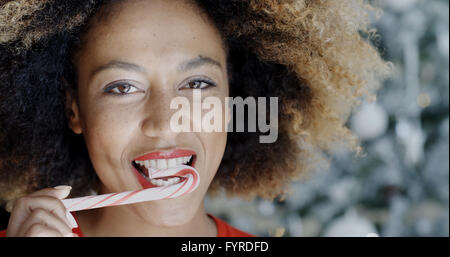 Giovane donna di mordere una festosa candy cane Foto Stock