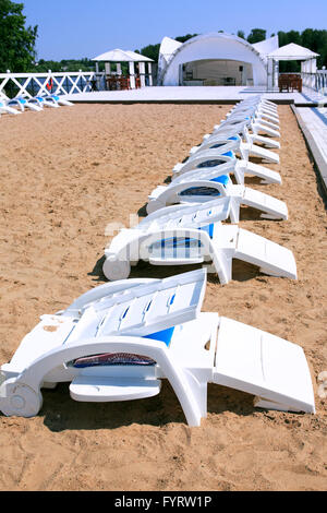 La vacanza estiva. Solarium esterno con vuoto in plastica sedie da spiaggia vicino al lago Foto Stock