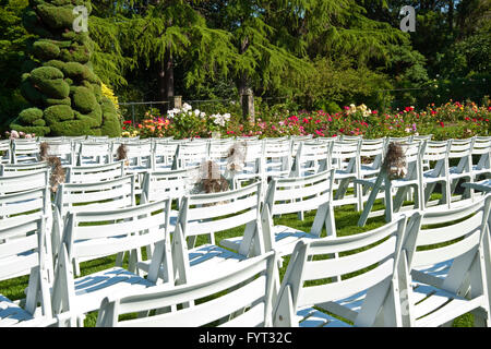 Righe di sedie nel parco nel bosco giardino di rose Foto Stock