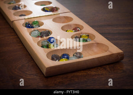 Mancala tradizionale tavolo con pezzi di vetro sul tavolo di legno Foto Stock