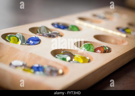 Mancala tradizionale tavolo con pezzi di vetro sul tavolo di legno Foto Stock