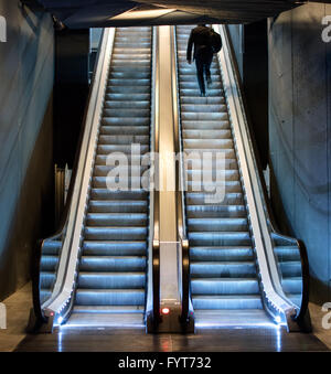 Uomo salire una scala mobile da una stazione della metropolitana a cavallo fino il battistrada in movimento verso la luce del giorno nella parte superiore, vista dal basso Foto Stock