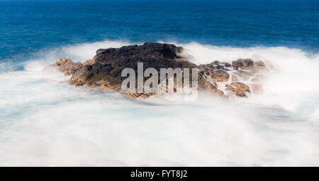 Lunga durata shot di onde che scorre sulla roccia di lava Foto Stock